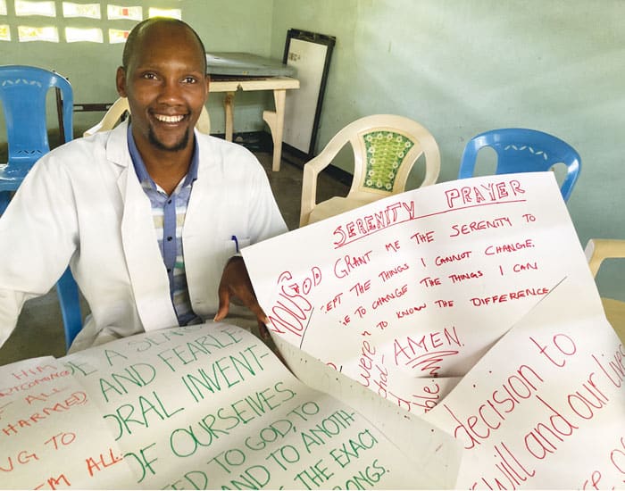 Psychologist Titus Ngugi, who invited Maryknoll Lay Missioner Megan Hamilton to Port Reitz, helps patients create signs from AA readings to hang on the walls of the facility. (Courtesy of Megan Hamilton/Kenya)