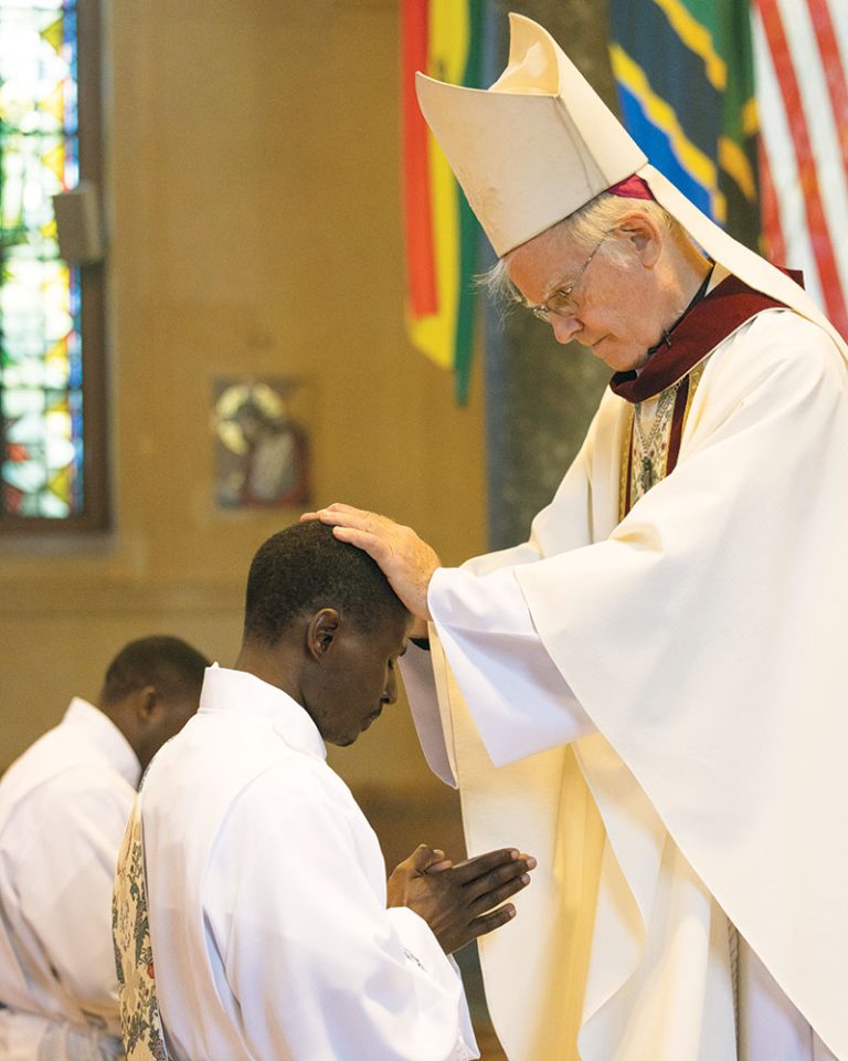 Auxiliary Bishop of New York Peter Byrne, the ordaining bishop, lays hands upon the two Maryknoll ordinands. 