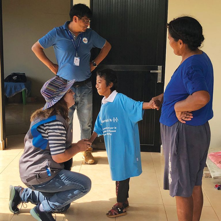 Siles shares a tender moment with Jhon Alex Muñoz as his mother, Doña Benita, looks on. Thanks to physical therapy, Jhon Alex can now walk. 
