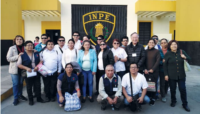 Father Kyungsu Son, in Roman collar, poses with students, teachers and assistants of Casa Bartimeo during a massage practice in Lima, Peru. (Courtesy of Kyungsu Son/Peru)