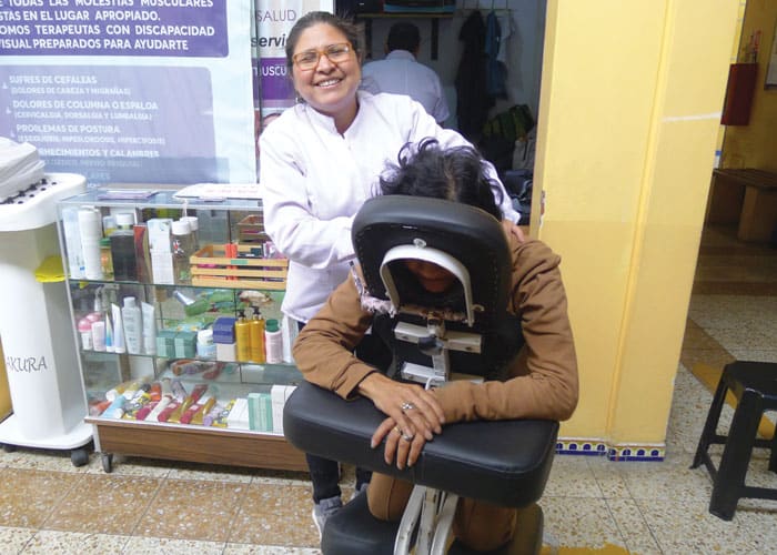 María Inés Aspilcueta demonstrates a short massage on her mother, Senaida Muñoz. Aspilcueta is able to earn a living thanks to the massage skills she learned after going blind at 26. (Lynn Monahan/Peru)