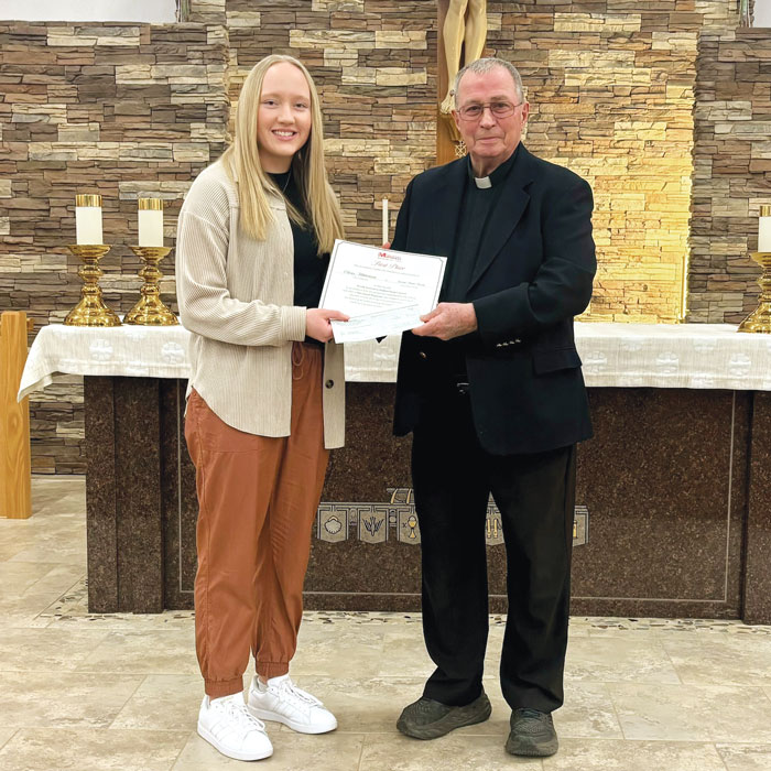 Maryknoll Father Donald Glover presents the Bishop Patrick J. Byrne Award to Olivia Mikkelsen, first-place essay winner for Division II. 