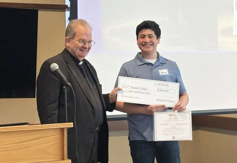 Maryknoll Father Kevin Hanlon presents Daniel Cobio with the Bishop Francis X. Ford Award for Division I at Holy Family Catholic Church, the Cobio family’s parish. 