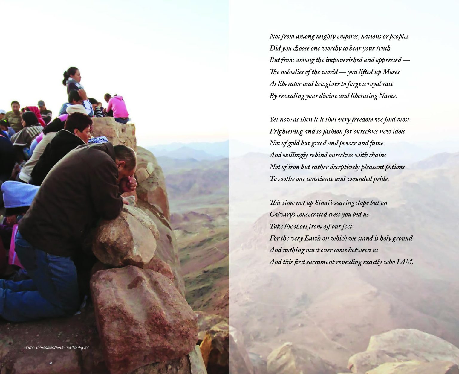 A group of people pray and gaze at a beautiful visa from atop a mountain.