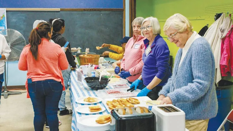 Voluntarios les sirven un desayuno caliente a migrantes que visitan el centro en búsqueda de ayuda. (Octavio Durán, OFM/EE. UU.)