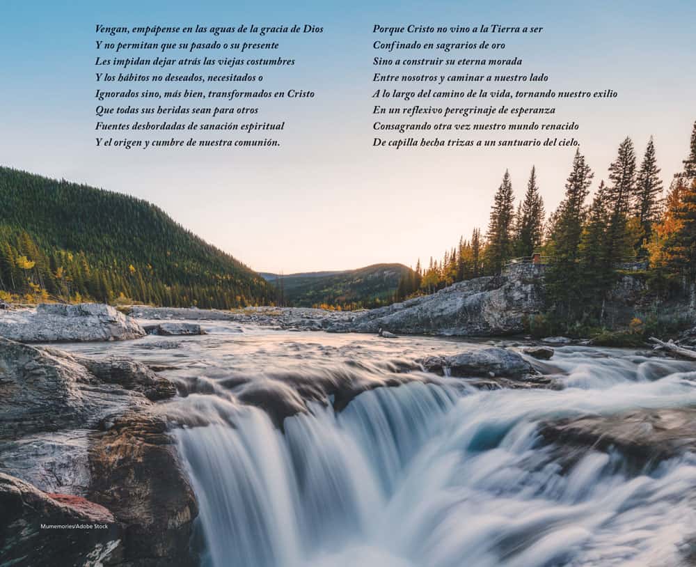 A small waterfall is framed by the rocky riverbed and majestic mountains and trees.