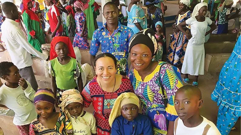 A group of colorfully clothed men, women, and children pose of a picture.