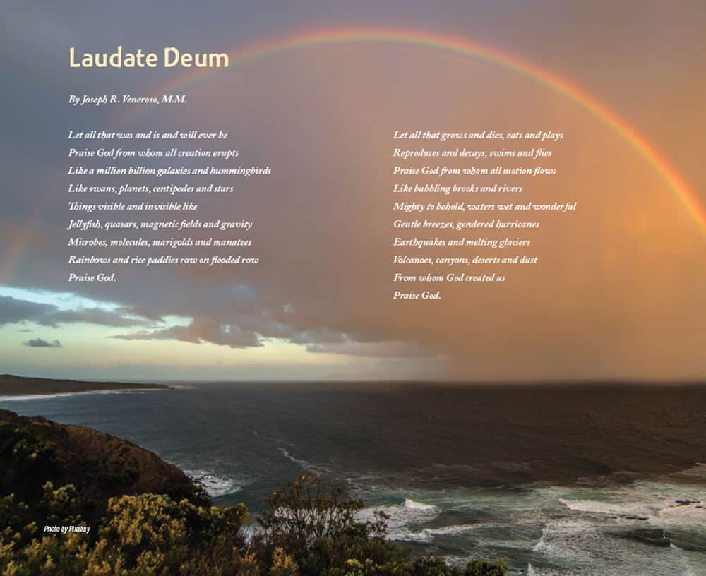A beautiful view of the ocean and shoreline with a long rainbow arching from the ocean to the shore.