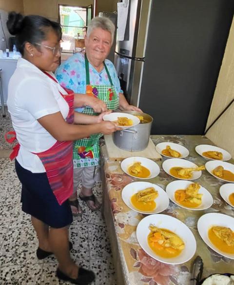 Maryknoll Sister Delia Marie “Dee” Smith, right, helps with the lunchtime program for residents and staff of a hospice she founded with another Maryknoll sister for people living with HIV/AIDS, Hospicio Santa Maria, in Pajapita, San Marcos, Guatemala. Sister Smith is seen with one of the cooks, Sara, who is not HIV-positive but who has lost relatives to HIV. (Photo courtesy of Dee Smith/Guatemala)