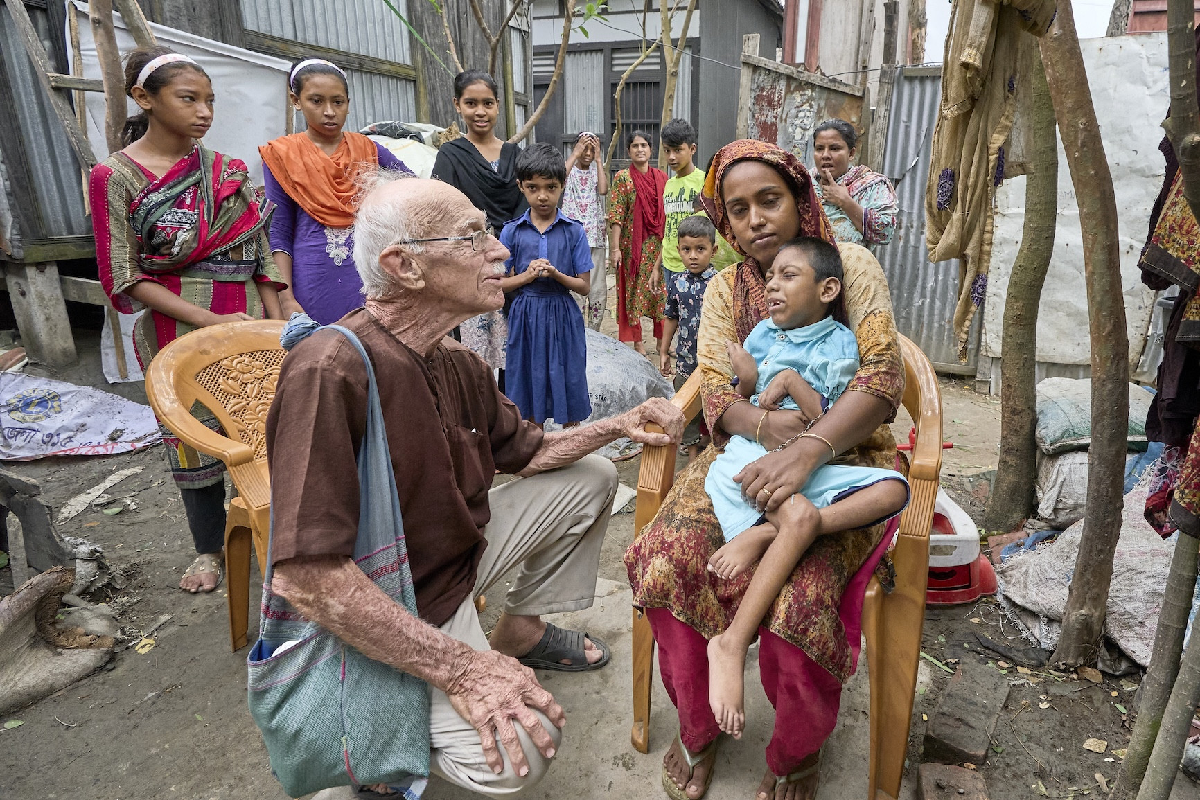 Maryknoll Father Robert McCahill visits 8-year-old Jair and his grandmother, Rohima, in the village of Batabhog near Srinagar. Father McCahill has spent five decades in Bangladesh helping poor families access medical care for children with disabilities. (Paul Jeffrey/Bangladesh)