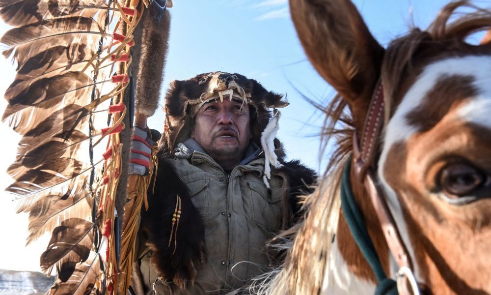 A Lakota person rides a horse with a sacred staff during a horse ride to meet Brad Upton, descendant of the commander of the Wounded Knee massacre on the Cheyenne River reservation in Eagle Butte, S.D., Nov. 6, 2019. Bishop Scott E. Bullock of Rapid City, S.D., and the state’s Jesuits, have condemned Defense Secretary Pete Hegseth’s decision to retain the Medal of Honor for the U.S. soldiers that massacred 300 Lakota people at Wounded Knee in 1890. (OSV News/Stephanie Keith, Reuters)
