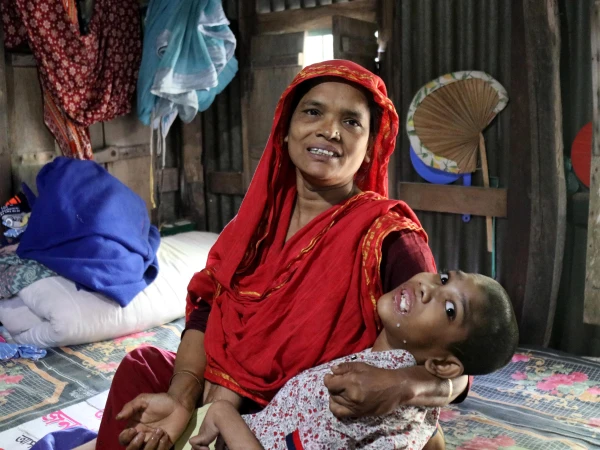 Abu Mosa Khan in his mother’s arms at their home in Munshigonj district, Bangladesh, on Nov. 18, 2025. Through Maryknoll Father Robert McCahill’s help, the family has access to free hospital treatment in Dhaka. (Stephan Uttom Rozario/Bangladesh)