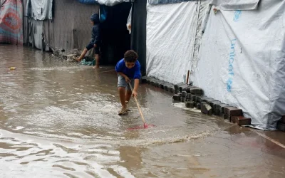 A young boy walks through a flooded path between UNICEF tents in Gaza.