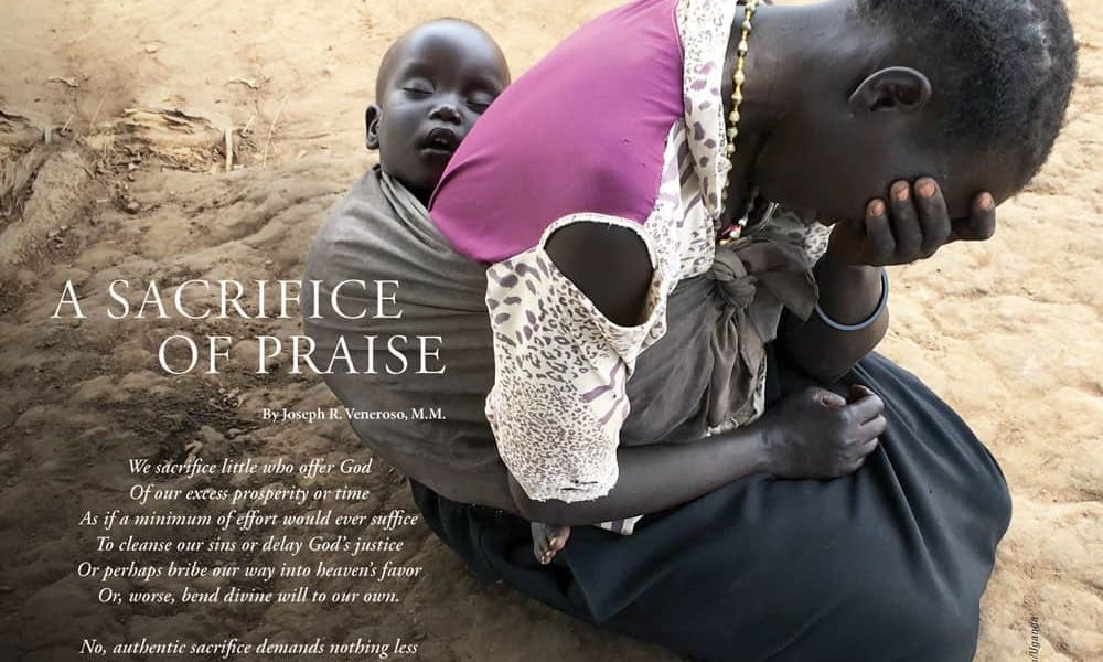 A woman sits on the ground in despair with a baby sleeping peacefully in a wrap on her back.