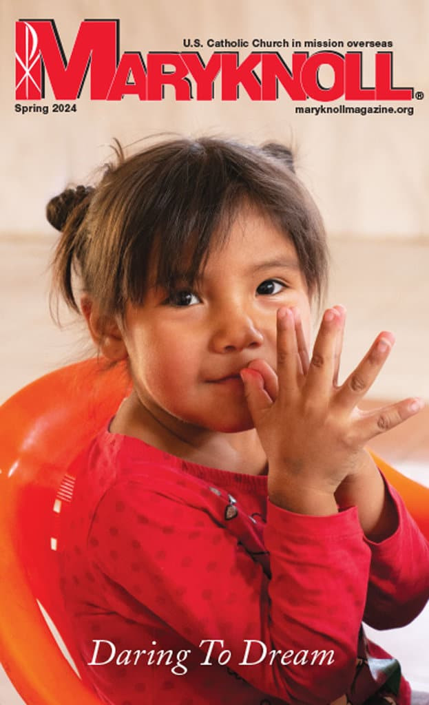 The Spring 2024 cover of Maryknoll Magazine with a picture of a beautiful baby girl with her palms together