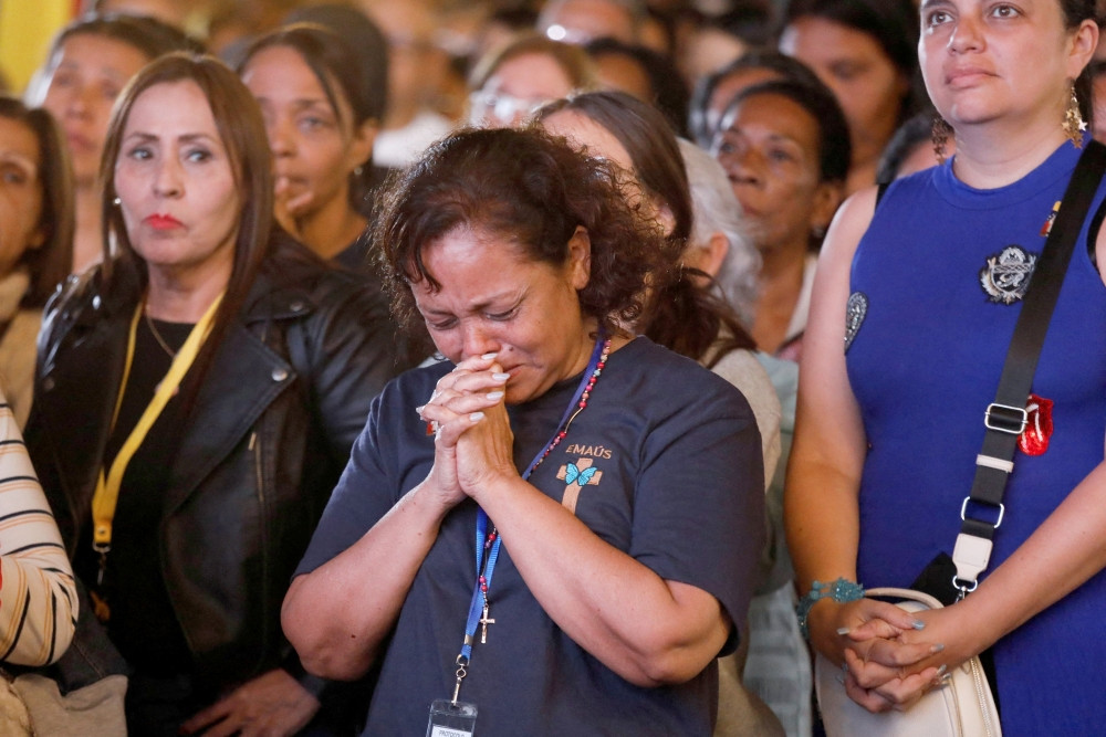 A woman prays during a Vatican canonization ceremony for Blessed José Gregorio Hernández, known as the “Doctor of the Poor,” and Blessed María Carmen Elena Rendiles Martínez as it is projected on a big screen in La Candelaria Square in Caracas, Venezuela, Oct. 19, 2025. At the Vatican Pope Leo XIV canonized the two Venezuelans along with five other blesseds. (OSV News/Leonardo Fernandez Viloria, Reuters)