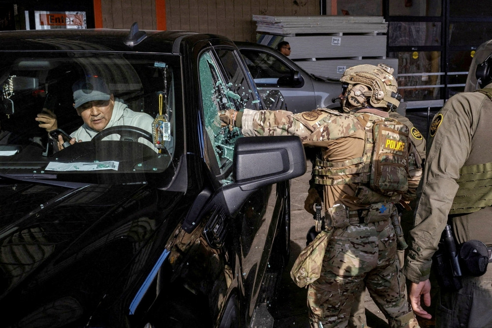 A U.S. federal agent smashes a car window while trying to detain a man during an immigration raid in Chicago, Dec. 17, 2025. An image of Mary and the Christ Child can be seen in the driver’s window. On Feb. 20, 2026, Bishop Brendan J. Cahill, chair of the U.S. Catholic bishops’ Committee on Migration, condemned the Trump administration’s plan for acquiring eight mega-detention centers for mass detention of immigrants, including families, it wants to deport. (OSV News/Jim Vondruska, Reuters)