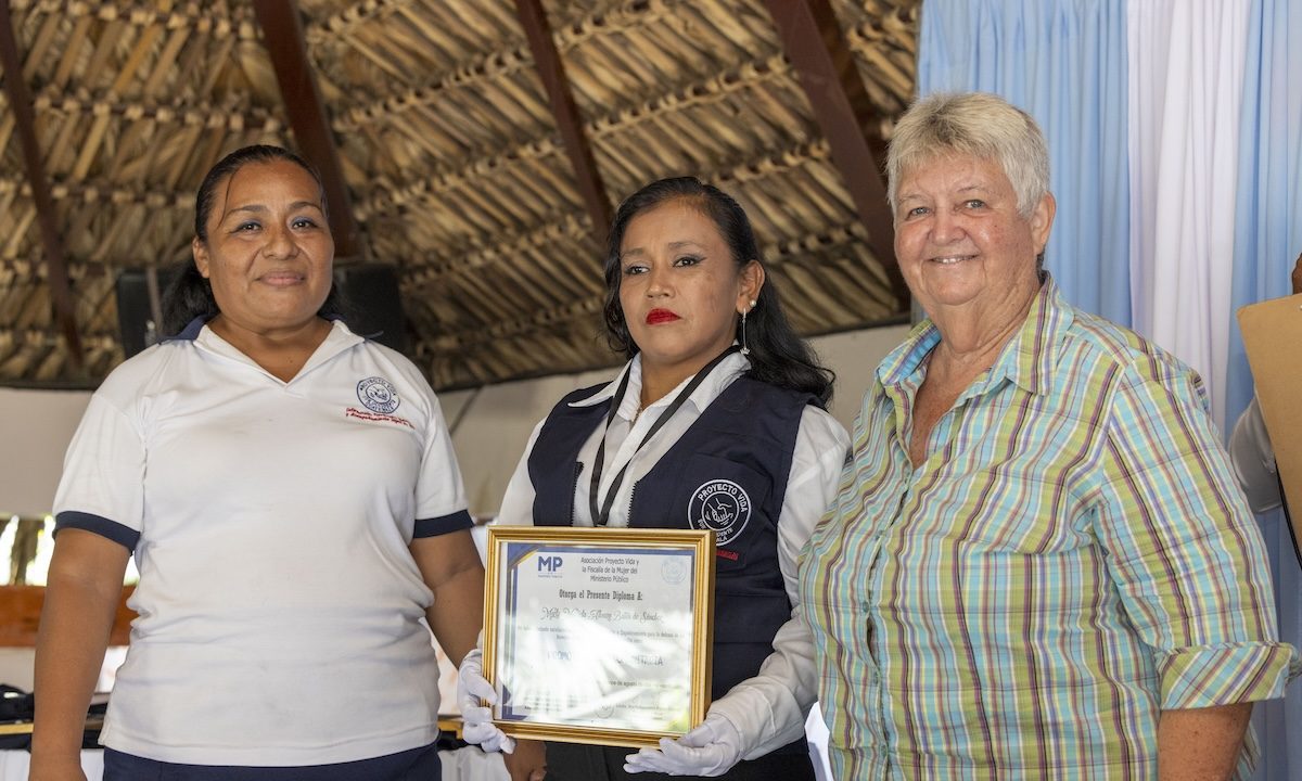 Luz Elizabeth “Lux” Hernández (left) and Maryknoll Sister Delia “Dee” Smith (right) formally instate a candidate as a community legal promoter, conferring a vest, identification badge and diploma. The program led by Lux and Sister Dee culminated in a graduation ceremony for 18 participants on Aug. 15, 2024, in the town of Pajapita in the department of San Marcos, Guatemala. (Octavio Durán/Guatemala)