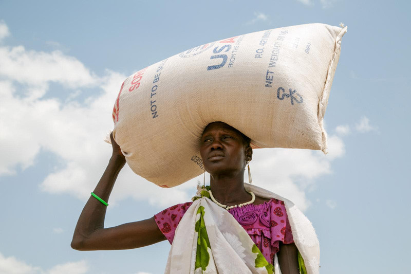 A woman carries food provided by U.S. Agency for International Development in Pajut, South Sudan, March 17, 2017. Catholic Relief Services has provided food assistance, with USAID funding, to communities and people returning to the area after being displaced during violence in 2013. (CNS photo/Nancy McNally, Catholic Relief Services)
