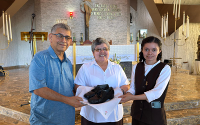 Franciscan Brother Octavio Durán presents the shoes St. Óscar Romero wore when he was martyred to Sister Tránsito de la Cruz (center), superior of the Missionary Carmelites of St. Teresa local community, and Sister Reina Mancía, caretaker of the memorial museum at Divine Providence Hospital in San Salvador, El Salvador. (Courtesy of Octavio Durán/El Salvador)