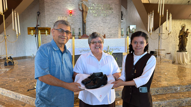 Franciscan Brother Octavio Durán presents the shoes St. Óscar Romero wore when he was martyred to Sister Tránsito de la Cruz (center), superior of the Missionary Carmelites of St. Teresa local community, and Sister Reina Mancía, caretaker of the memorial museum at Divine Providence Hospital in San Salvador, El Salvador. (Courtesy of Octavio Durán/El Salvador)