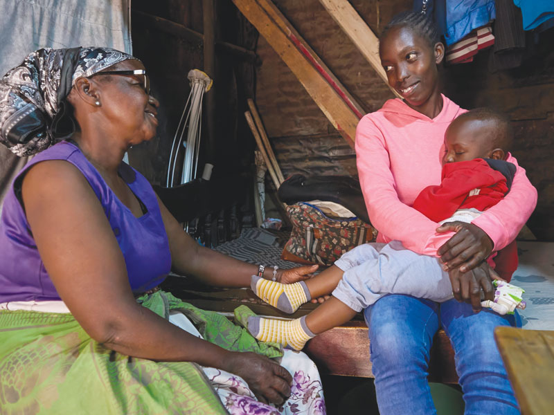 Josephine Kamau visits Stacy Adhiambo and 1-year-old Byalian at their home in the Mathare slum. Adhiambo was born HIV positive but didn’t learn her status until 2005. She started on antiretroviral treatment, which later enabled her son to be born without the virus. (Paul Jeffrey/Kenya)