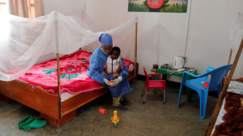 Noella Kavira Kitakya, 26, an Ebola survivor who works as a caregiver, puts a shoe on a child whose mother died of Ebola at a UNICEF center in Katwa, Congo, in this Oct. 2, 2019, file photo. Pope Francis opened a new path to sainthood in 2017 for “martyrs of charity,” those who made heroic sacrifices during pandemics and other situations of contagion. (CNS/Zohra Bensemra, Reuters)