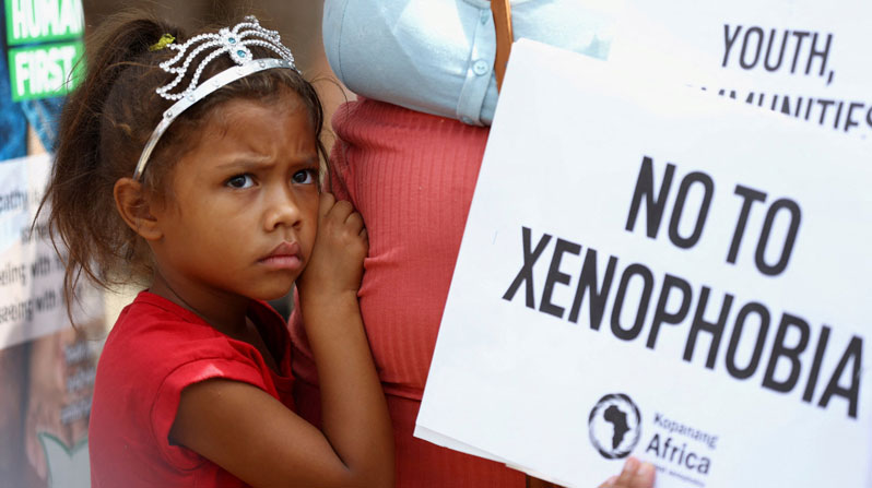 A child looks on next to her mother, who is holding a placard, during a protest march by members of a South African anti-xenophobia organization in Johannesburg March 26, 2022. The march followed a campaign by another group that called on the government to prioritize jobs for nationals and remove immigrants who are in the country without authorization. (OSV News/Siphiwe Sibeko, Reuters)