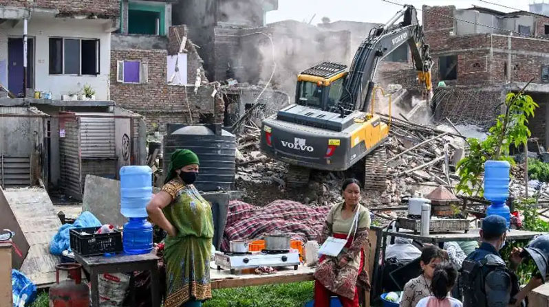People watch as heavy construction equipment is used to demolish squatter settlements near the Bagmati River in Kathmandu on May 1. Nepali authorities have been demolishing informal settlements of thousands of people across the nation, despite criticism from rights groups. (Prakash Mathema/AFP/Via UCANews/Nepal)
