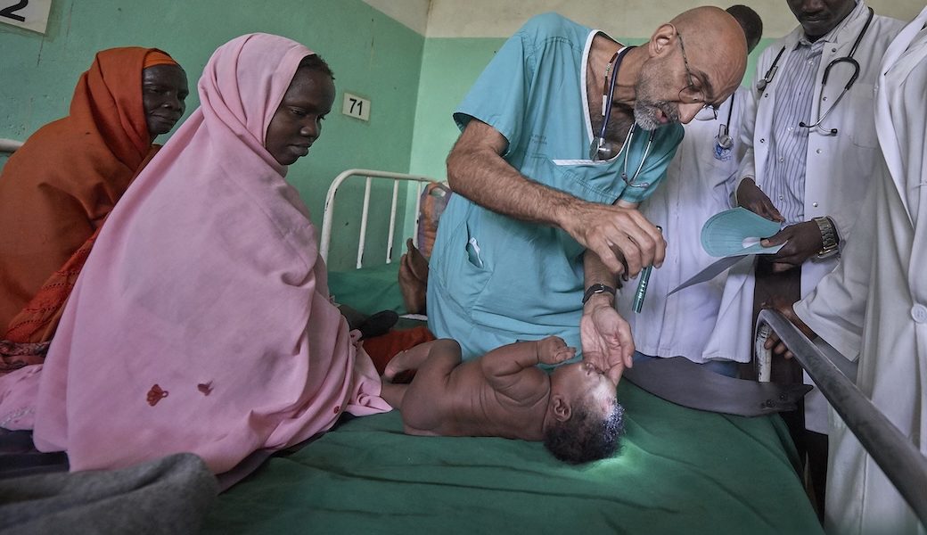 Dr. Tom Catena, a Catholic lay missionary from the United States, examines a baby during rounds in late April at the Mother of Mercy Hospital in Gidel, a village in the Nuba Mountains of Sudan. The Catholic hospital, at which Catena is often the only physician, is the only referral hospital in the war-torn area. (CNS/Paul Jeffrey/Sudan)