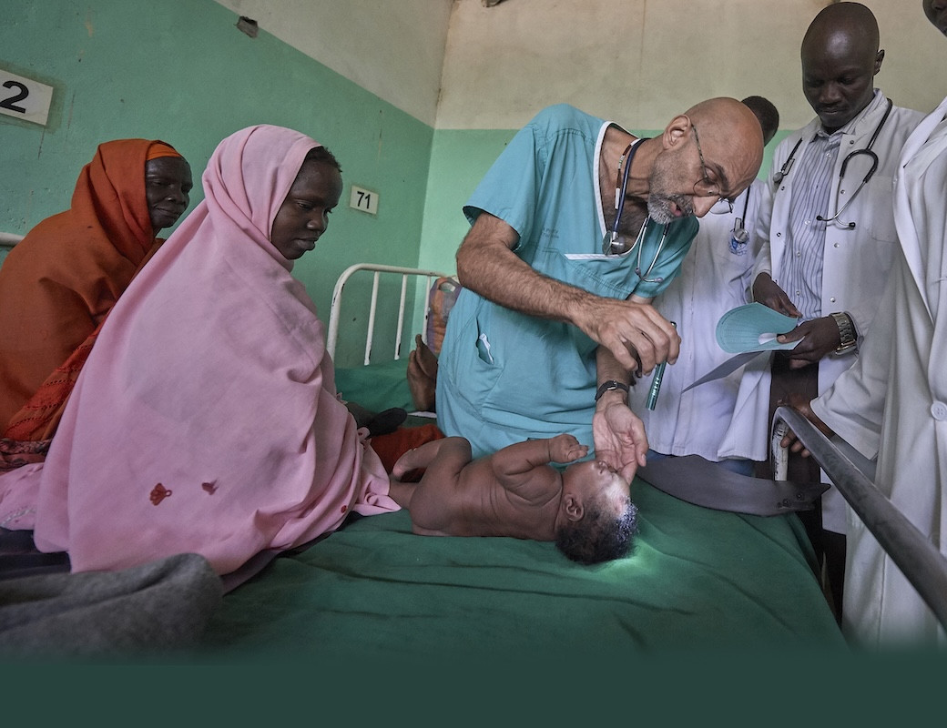 Dr. Tom Catena, a Catholic lay missionary from the United States, examines a baby during rounds in late April at the Mother of Mercy Hospital in Gidel, a village in the Nuba Mountains of Sudan. The Catholic hospital, at which Catena is often the only physician, is the only referral hospital in the war-torn area. (CNS/Paul Jeffrey/Sudan)