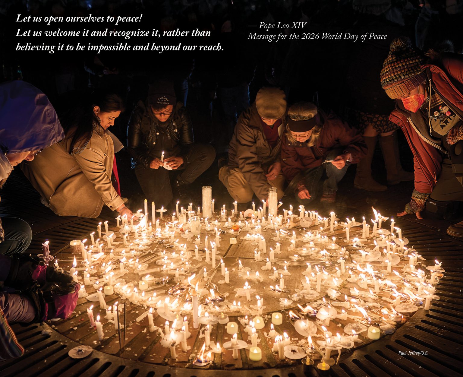 A group of people kneel while placing candles among a large circle of candles on the ground.