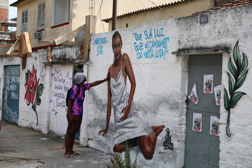 A man touches artwork made by artists in honor of Kathlen Romeu in a poor section of Rio de Janeiro June 14, 2021. The 24-year-old interior designer was pregnant when she was shot dead June 8 during a police operation, according to local media. The graffiti reads: “May your light guide the paths of our fight.” (CNS/Pilar Olivares, Reuters)