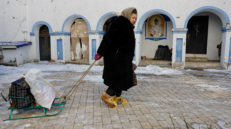An elderly woman pulls a sled with her belongings during the distribution of humanitarian aid brought by volunteers outside a church in Luhansk, Ukraine. (OSV News/Alexander Ermochenko, Reuters)