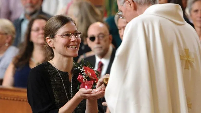 Maryknoll Sister Julia Shideler smiles as she receives communion from the late Maryknoll Father John (Jack) Sullivan during her Profession of Perpetual Vows Mass on September 28, 2014, at the Maryknoll Sisters Center in Ossining, New York. (Gregory A. Shemitz/CNS/U.S.)
