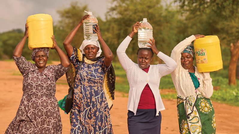 Women carry the jugs they filled at the community water point at Christ the King Church in Kavete. (Paul Jeffrey/Kenya)