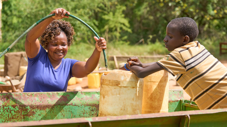 Mary Simon fills jerry cans with fresh water at St. Michael the Archangel Church in Kamboo, Kenya, where the Maryknoll Society has financed a well and storage system. (Paul Jeffrey/Kenya)