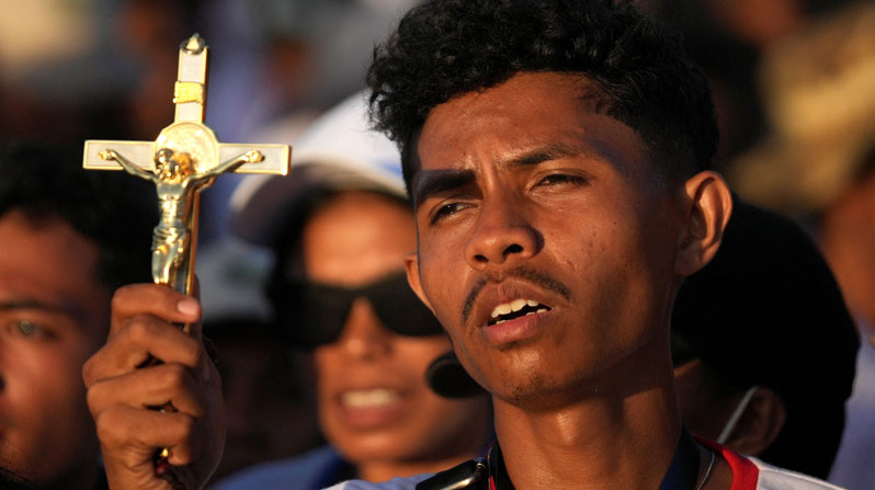 A man holds a crucifix as Pope Francis celebrates Mass at Taci Tolu Park in Dili, East Timor, during the pope’s 2024 apostolic trip. (OSV News/Dita Alangkara/Reuters/East Timor)