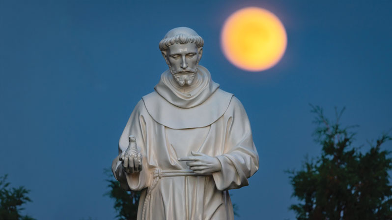 A hunter’s moon rises behind a statue of St. Francis of Assisi outside the National Shrine of Our Lady of Champion in Champion, Wisconsin. (OSV News/Sam Lucero/CNS/U.S.)