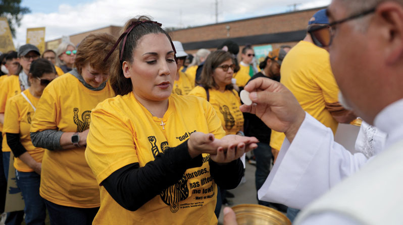 A priest distributes Communion to Catholics who participated in a Eucharistic procession to an immigration detention facility in Chicago. (OSV/Jeenah Moon/Reuters)