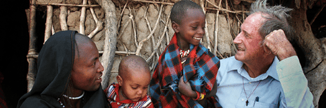 Fr. Dan Ohmann in a refugee camp in Tanzania talking with a father and his two sons