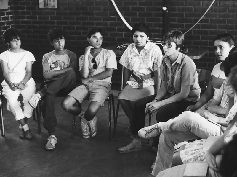 La Hermana Maryknoll Linda Donovan, quien sirvió en los barrios marginales de Santiago, charla con adolescentes en 1987. Ella lideró programas para la juventud. (Shirley King/Chile)