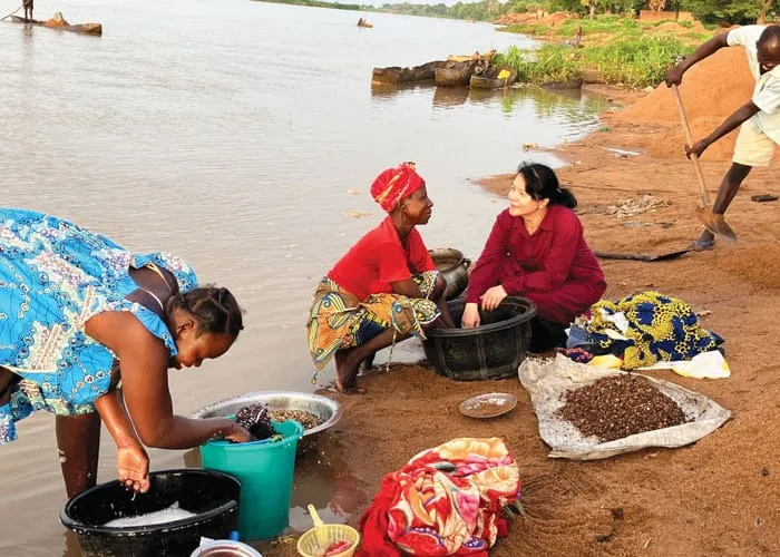 La Hermana Maryknoll NgocHà Pham (derecha) visita el río Logone, donde muchas personas locales pescan, lavan ropa, preparan comida y recolectan grava para fabricar ladrillos. (Cortesía de NgocHà Pham/Chad)