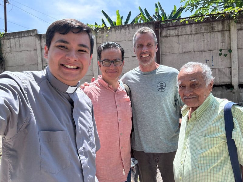 Izq.: El Padre Jonathan Vásquez, el Misionero Laico Maryknoll Bob Cunningham (centro) y otros dos voluntarios  sirven en una cárcel juvenil en El Salvador. (Cortesía de Robert Cunningham/El Salvador)