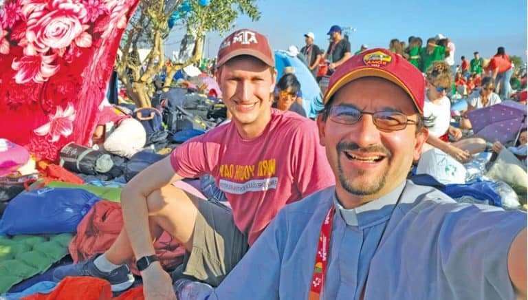 Stephen Harden, seminarista Maryknoll, y el Padre Maryknoll Rodrigo Ulloa-Chavarry asisten a la vigilia en el Parque Tejo junto con una multitud de otros peregrinos de todo el mundo. (Rodrigo Ulloa-Chavarry, M.M./Portugal)