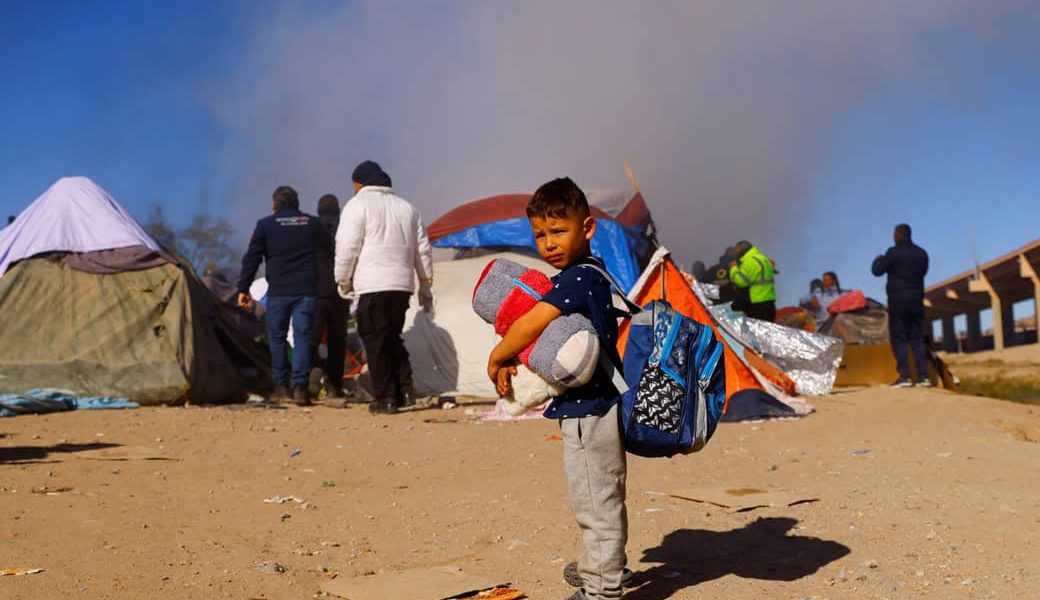 Un niño en Ciudad Juárez, México, permanece de pie mientras la policía desaloja a migrantes de un campamento a orillas del Río Bravo el 27 de noviembre del 2022. (CNS/José Luis González, Reuters)