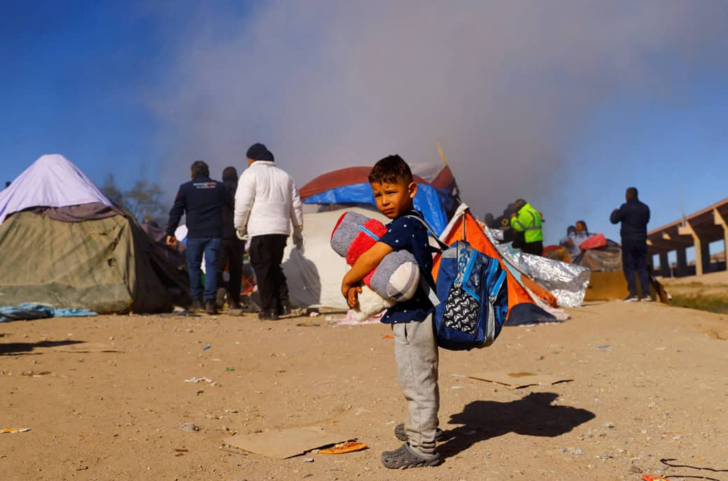 Un niño en Ciudad Juárez, México, permanece de pie mientras la policía desaloja a migrantes de un campamento a orillas del Río Bravo el 27 de noviembre del 2022. (CNS/José Luis González, Reuters)