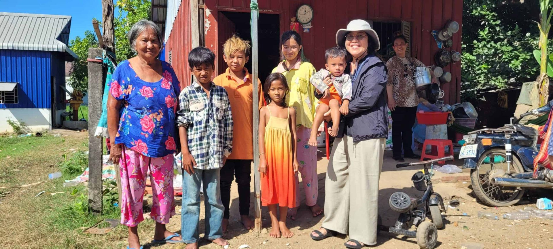 La misionera laica Maryknoll Thu Tam Hoang (derecha, con sombrero) visita a una familia en Cambodia, donde llegó en 2024 en su primera asignación para la organización misionera. Hoang, cuya familia huyó de Vietnam en 1975, trabajó en Estados Unidos en una carrera que incluía servicios de reasentamiento a refugiados. Como católica conversa, valora el enfoque de la organización religiosa misionera. (Cortesía de los Misioneros Laicos Maryknoll/Cambodia)