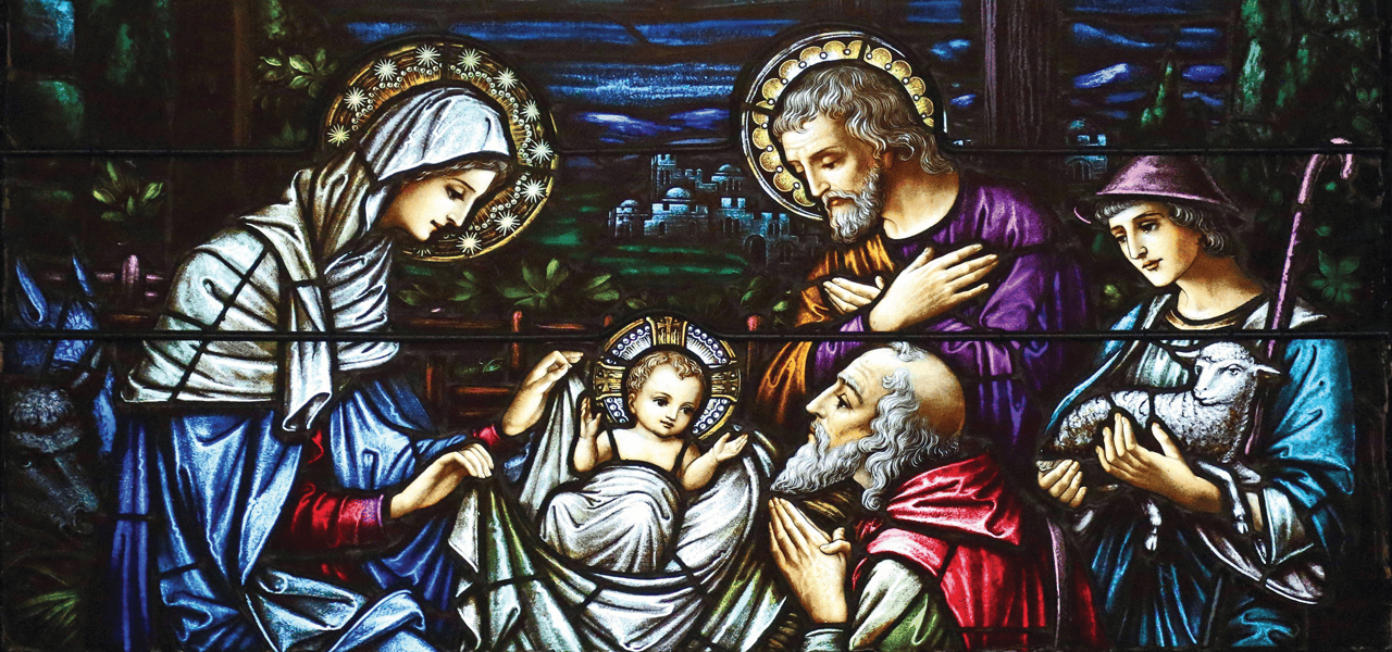 Una hermosa imagen de vidrieras de María, José y otros reunidos en un pesebre rodeando al niño Jesús