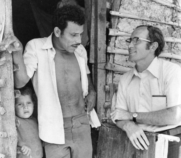 El Padre Spain con una familia en Tutunichapa, San Salvador, habitada por personas desplazadas por la guerra y los terremotos. (Eric Wheater/El Salvador)